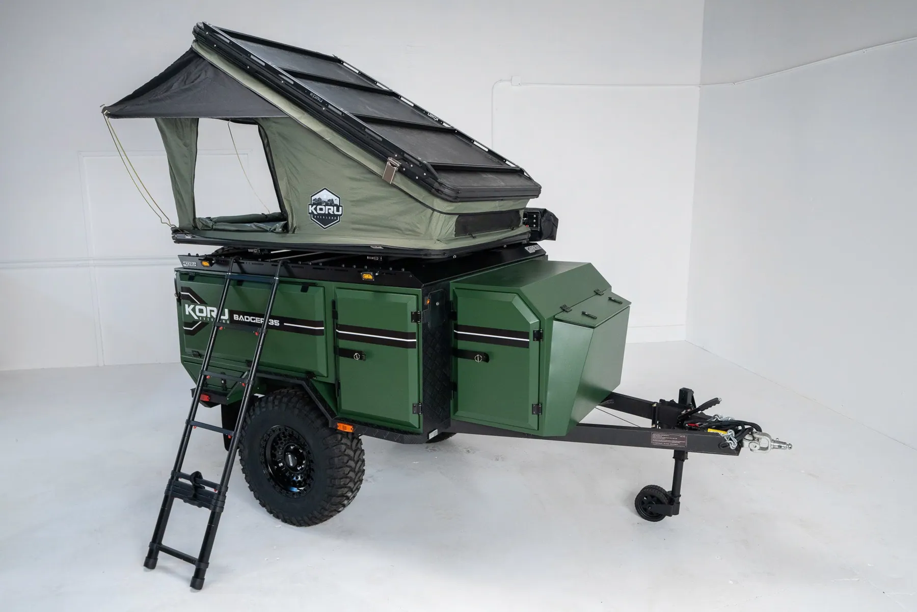 Off-road trailer with rooftop tent and awning deployed as a small team base camp