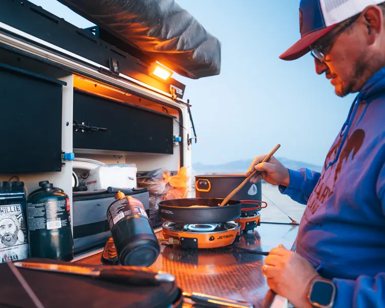 Trailer camp kitchen with stove and refrigeration set up under an awning